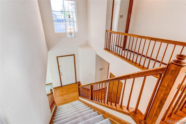 stairs featuring wood finished floors and a towering ceiling