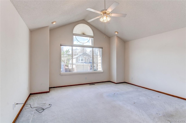 carpeted empty room featuring lofted ceiling, baseboards, a ceiling fan, and a textured ceiling