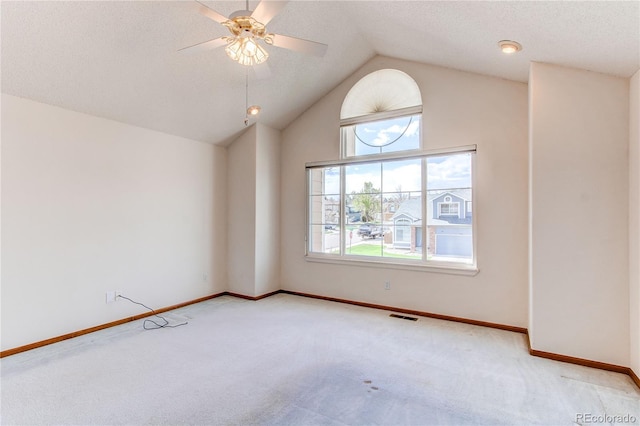 carpeted empty room with a ceiling fan, baseboards, and vaulted ceiling
