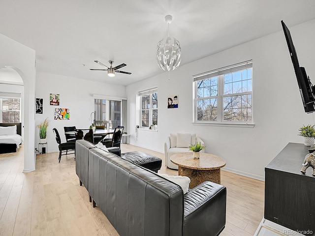 living room with light wood-type flooring, arched walkways, and a wealth of natural light