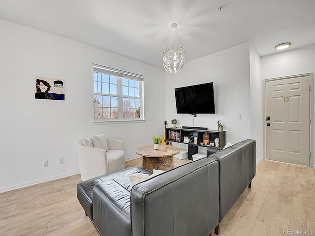 living area featuring light wood-style floors, a chandelier, and baseboards