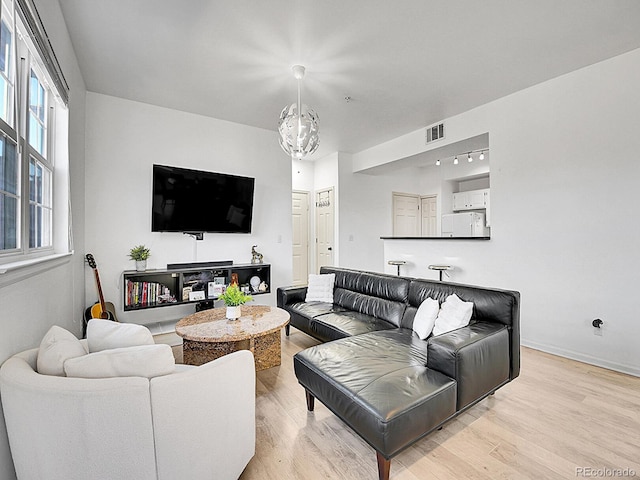 living area featuring a chandelier, visible vents, and light wood-style flooring