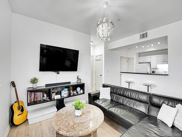 living room with visible vents, a notable chandelier, baseboards, and wood finished floors