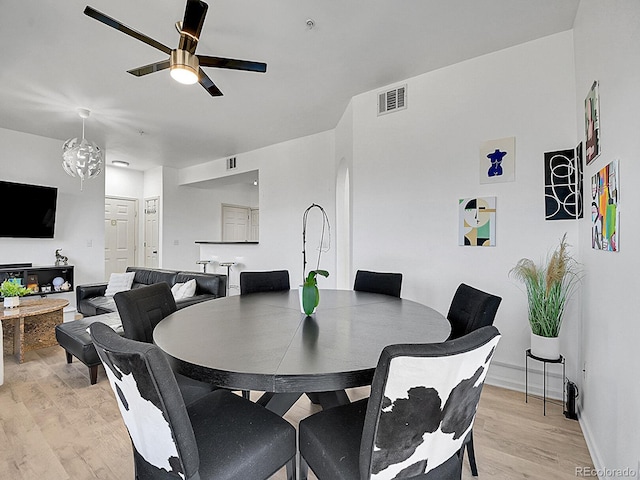 dining space featuring a ceiling fan, arched walkways, visible vents, and light wood-style flooring