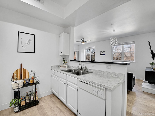 kitchen featuring light wood finished floors, a peninsula, white dishwasher, white cabinetry, and a sink