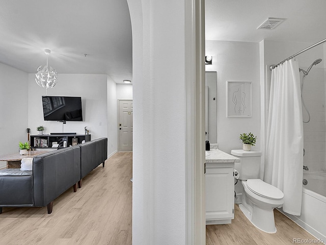 bathroom featuring toilet, wood finished floors, vanity, visible vents, and shower / bath combo with shower curtain