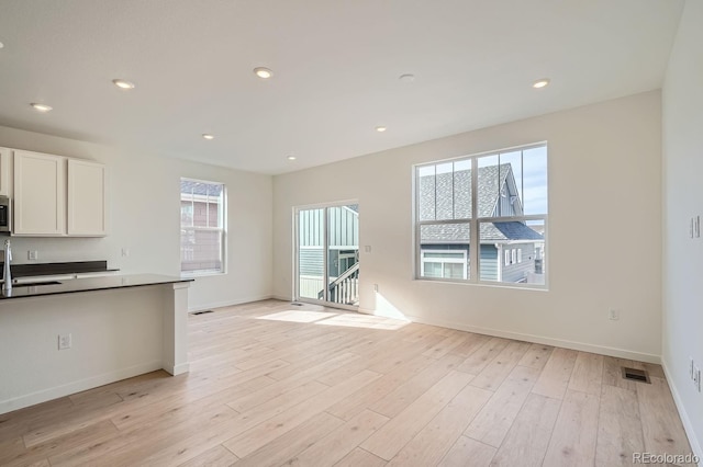 kitchen with sink, white cabinets, and light hardwood / wood-style flooring