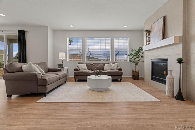 living room with baseboards, a tile fireplace, light wood-style flooring, and recessed lighting