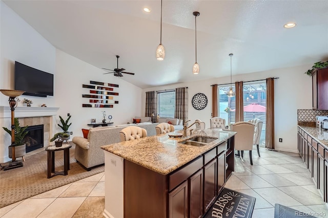 kitchen with a fireplace, lofted ceiling, ceiling fan, decorative light fixtures, and sink