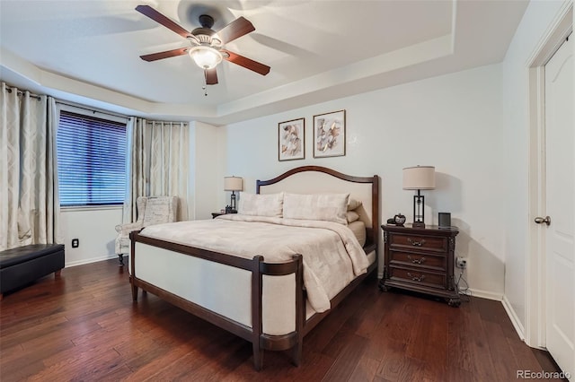 bedroom with a tray ceiling, ceiling fan, and dark hardwood / wood-style flooring