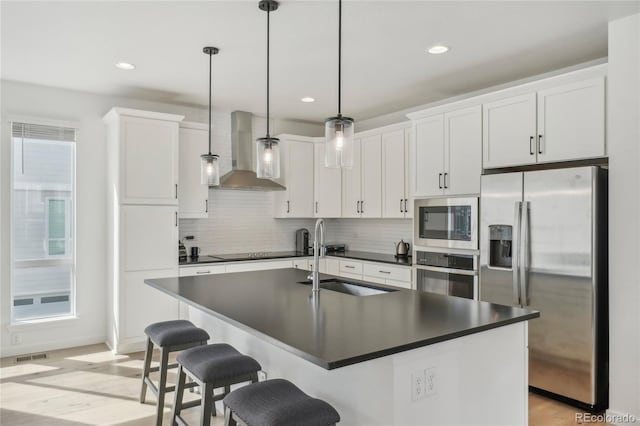 kitchen featuring a sink, stainless steel appliances, dark countertops, wall chimney range hood, and backsplash