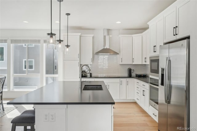 kitchen featuring a sink, dark countertops, stainless steel appliances, wall chimney exhaust hood, and white cabinets