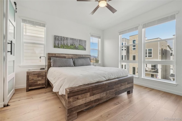 bedroom featuring light wood-type flooring, baseboards, and ceiling fan