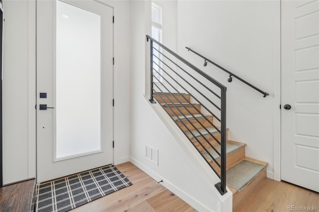 entryway featuring visible vents, stairway, baseboards, and wood finished floors