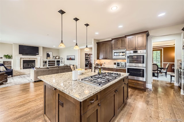 1410 S Elizabeth St, Denver, CO 80210 - kitchen with appliances with stainless steel finishes, light wood finished floors, light stone countertops, dark brown cabinets, and recessed lighting