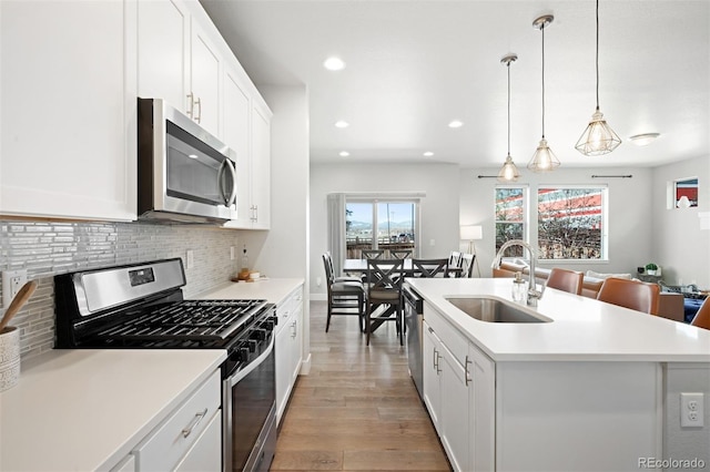 kitchen featuring stainless steel appliances, a kitchen island with sink, sink, light hardwood / wood-style floors, and white cabinetry