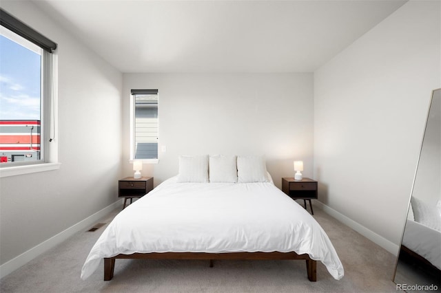 bedroom featuring light carpet and multiple windows