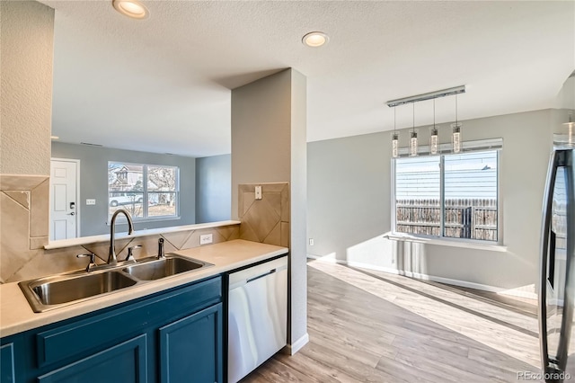 kitchen with sink, light hardwood / wood-style flooring, dishwasher, a textured ceiling, and blue cabinets