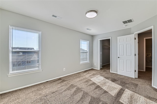 unfurnished bedroom with a spacious closet, carpet floors, and a closet