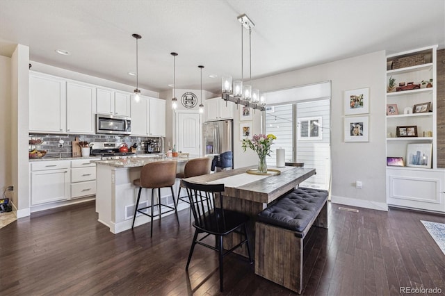6834 Clay St N, Denver, CO 80221 - kitchen with appliances with stainless steel finishes, dark wood finished floors, white cabinetry, a center island with sink, and recessed lighting