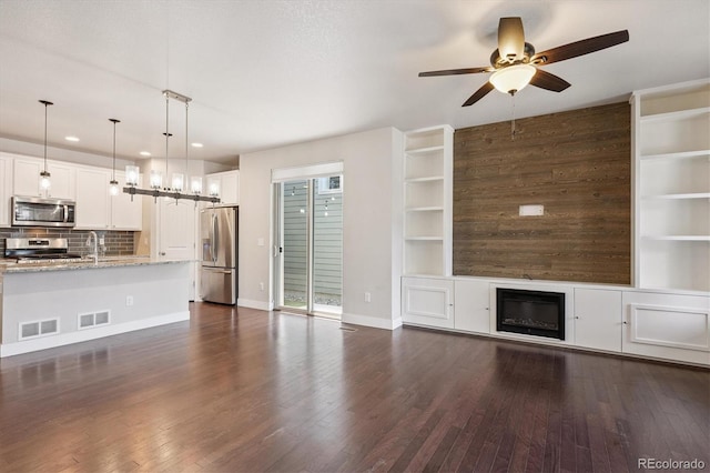6834 Clay St N, Denver, CO 80221 - unfurnished living room featuring ceiling fan, recessed lighting, dark wood finished floors, built in features, and a glass covered fireplace