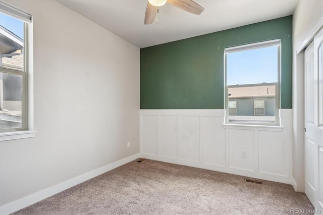6834 Clay St N, Denver, CO 80221 - unfurnished room featuring plenty of natural light, carpet flooring, a ceiling fan, a wainscoted wall, and a decorative wall