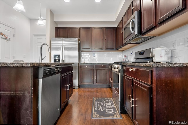 kitchen featuring hanging light fixtures, appliances with stainless steel finishes, tasteful backsplash, dark hardwood / wood-style flooring, and dark brown cabinetry