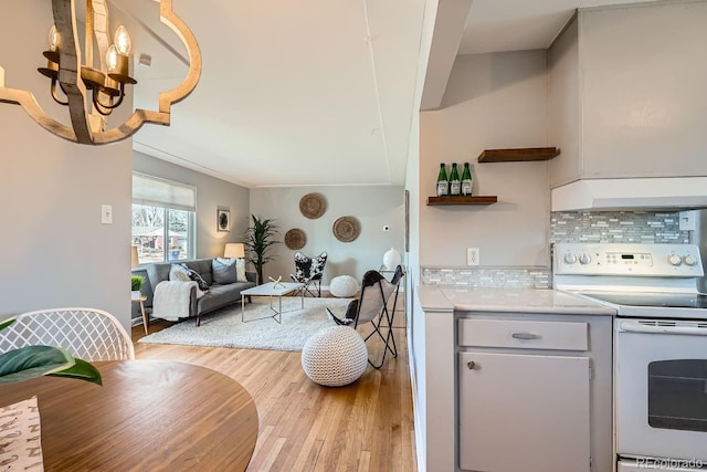 kitchen with light wood-style flooring, open shelves, under cabinet range hood, white electric stove, and light countertops