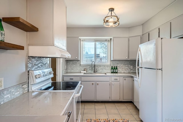 kitchen with under cabinet range hood, light countertops, decorative backsplash, white appliances, and a sink