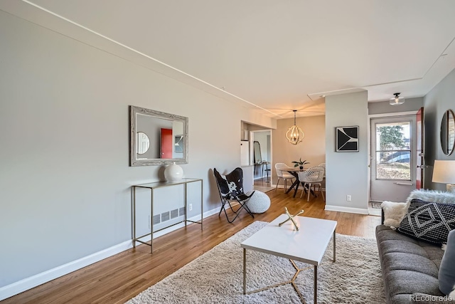 living room featuring baseboards, an inviting chandelier, and wood finished floors