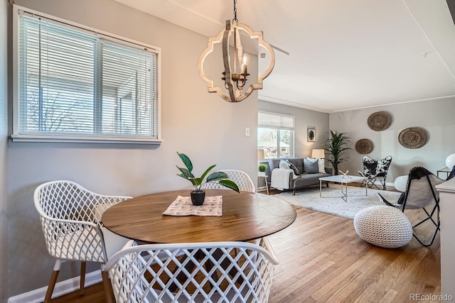 dining area with baseboards, an inviting chandelier, and wood finished floors