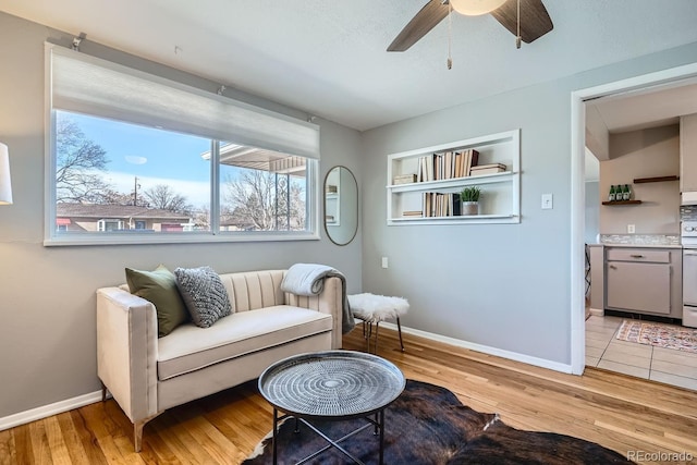 living area with baseboards, light wood-style floors, and a ceiling fan