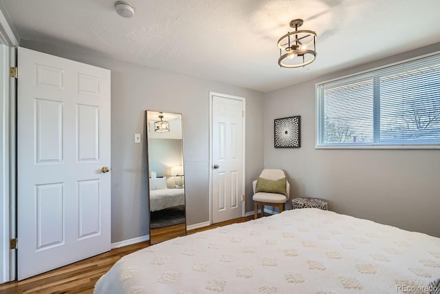 bedroom with wood finished floors, baseboards, a closet, and a textured ceiling