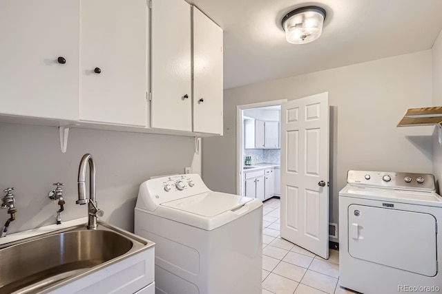 laundry room with washing machine and clothes dryer, light tile patterned floors, cabinet space, and a sink