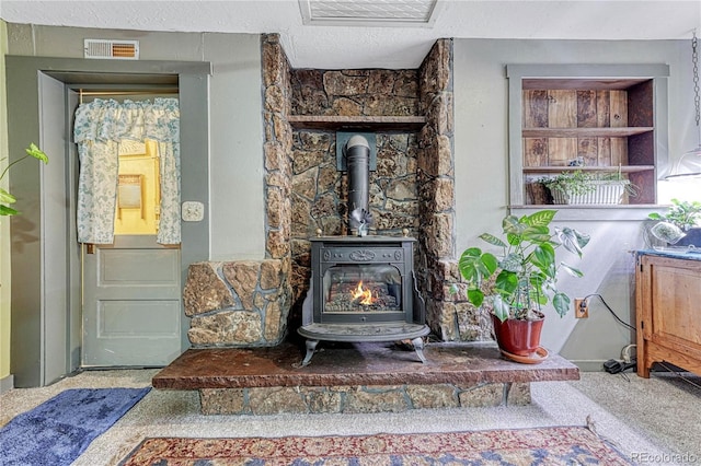 interior details with a wood stove, carpet, and a textured ceiling