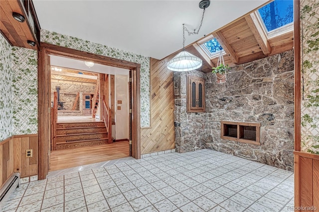 interior space with wooden ceiling, wooden walls, light hardwood / wood-style floors, a baseboard radiator, and a stone fireplace