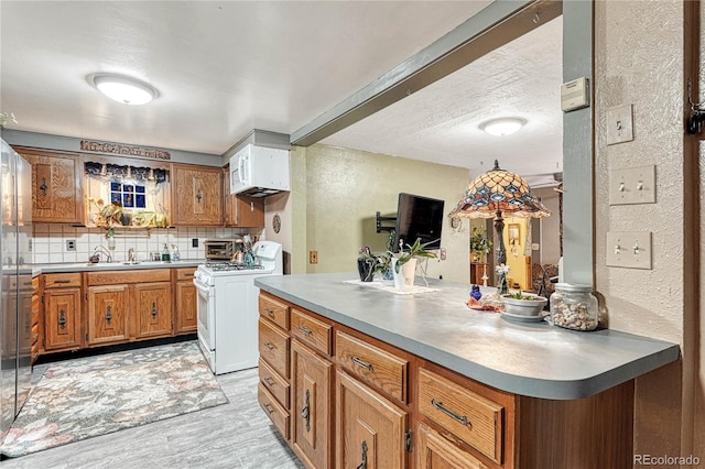 kitchen featuring sink, light hardwood / wood-style flooring, white range with gas stovetop, and decorative backsplash