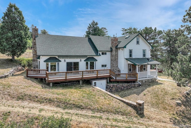 back of property with a wooden deck and a yard