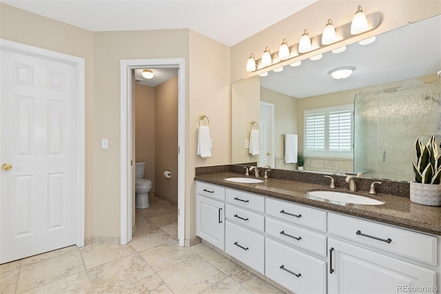 full bath with toilet, a shower stall, double vanity, and a sink