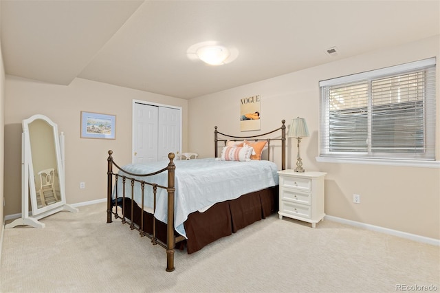 bedroom with a closet, light colored carpet, visible vents, and baseboards