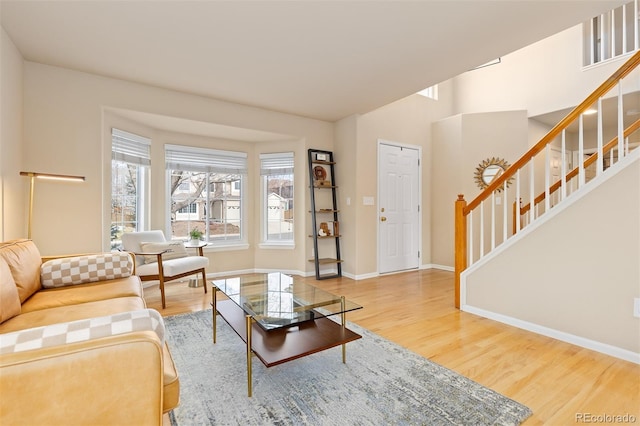 living area with baseboards, stairway, and wood finished floors