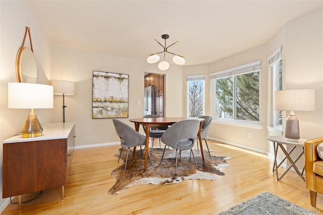 dining space with a chandelier, light wood-type flooring, and baseboards