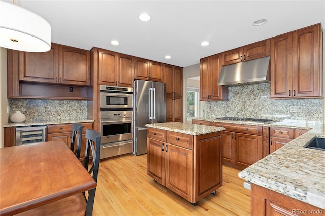 kitchen featuring wine cooler, a warming drawer, stainless steel appliances, light wood-style floors, and under cabinet range hood