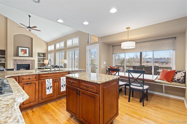 kitchen featuring brown cabinetry, light wood-style floors, open floor plan, and a sink