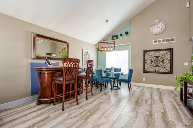 dining area with a dry bar, high vaulted ceiling, baseboards, and visible vents