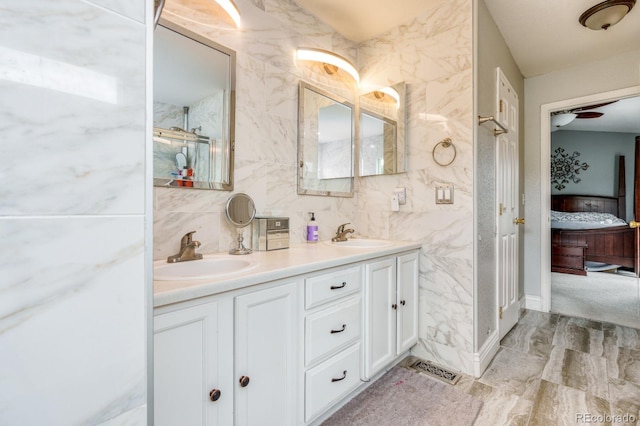 bathroom with double vanity, a sink, tile walls, and connected bathroom