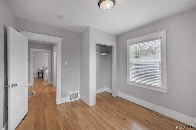 unfurnished bedroom with a closet, light wood-style floors, and baseboards