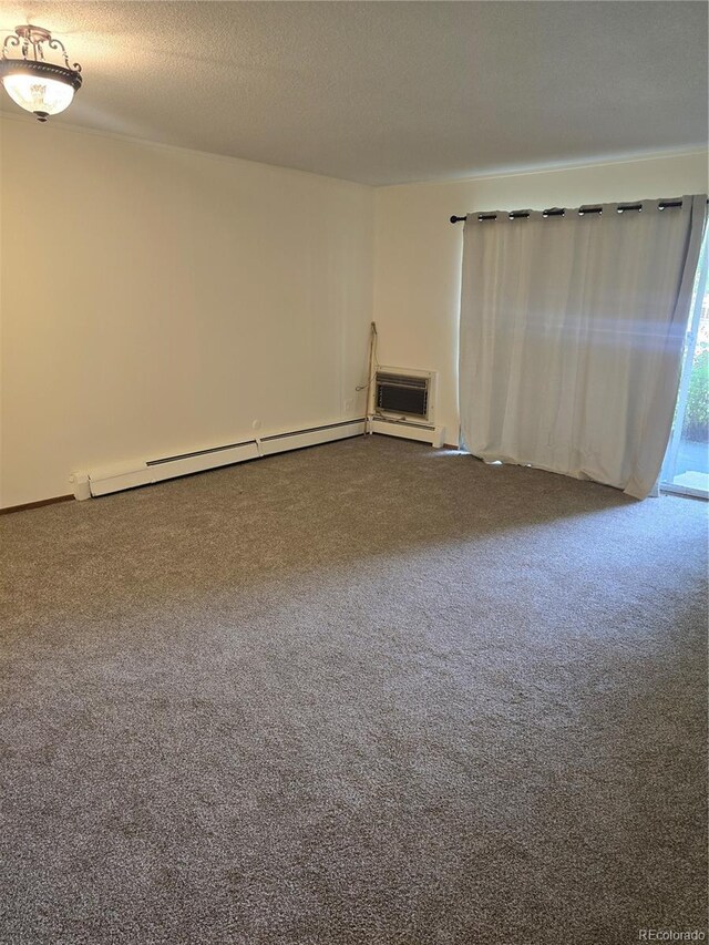 empty room with a wall unit AC, carpet, a textured ceiling, and a baseboard heating unit