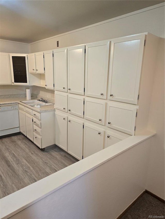 kitchen featuring dishwasher, backsplash, sink, white cabinetry, and wood-type flooring