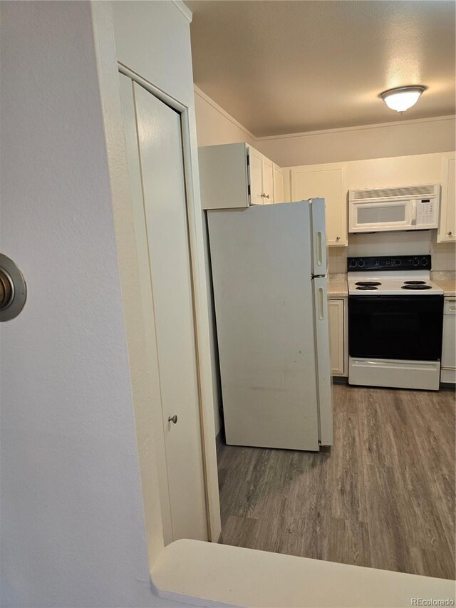 kitchen featuring white cabinets, white appliances, and hardwood / wood-style flooring